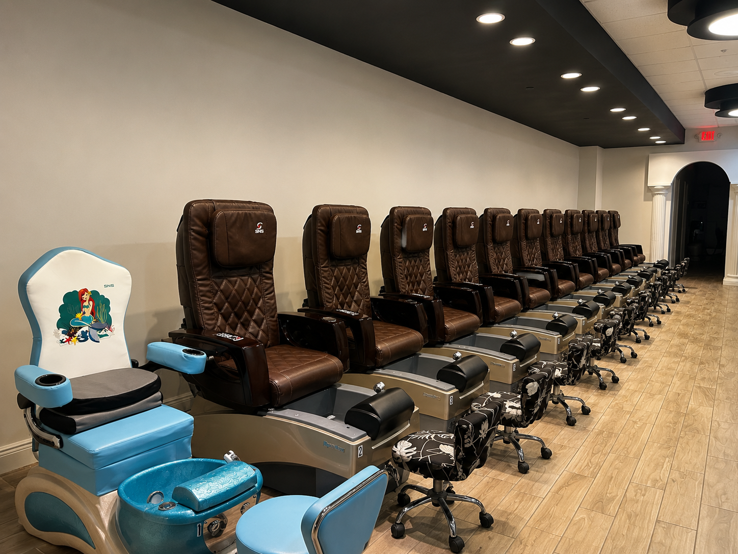 Ocean Nails pedicure area with a row of brown massage chairs and a child-sized Ariel chair