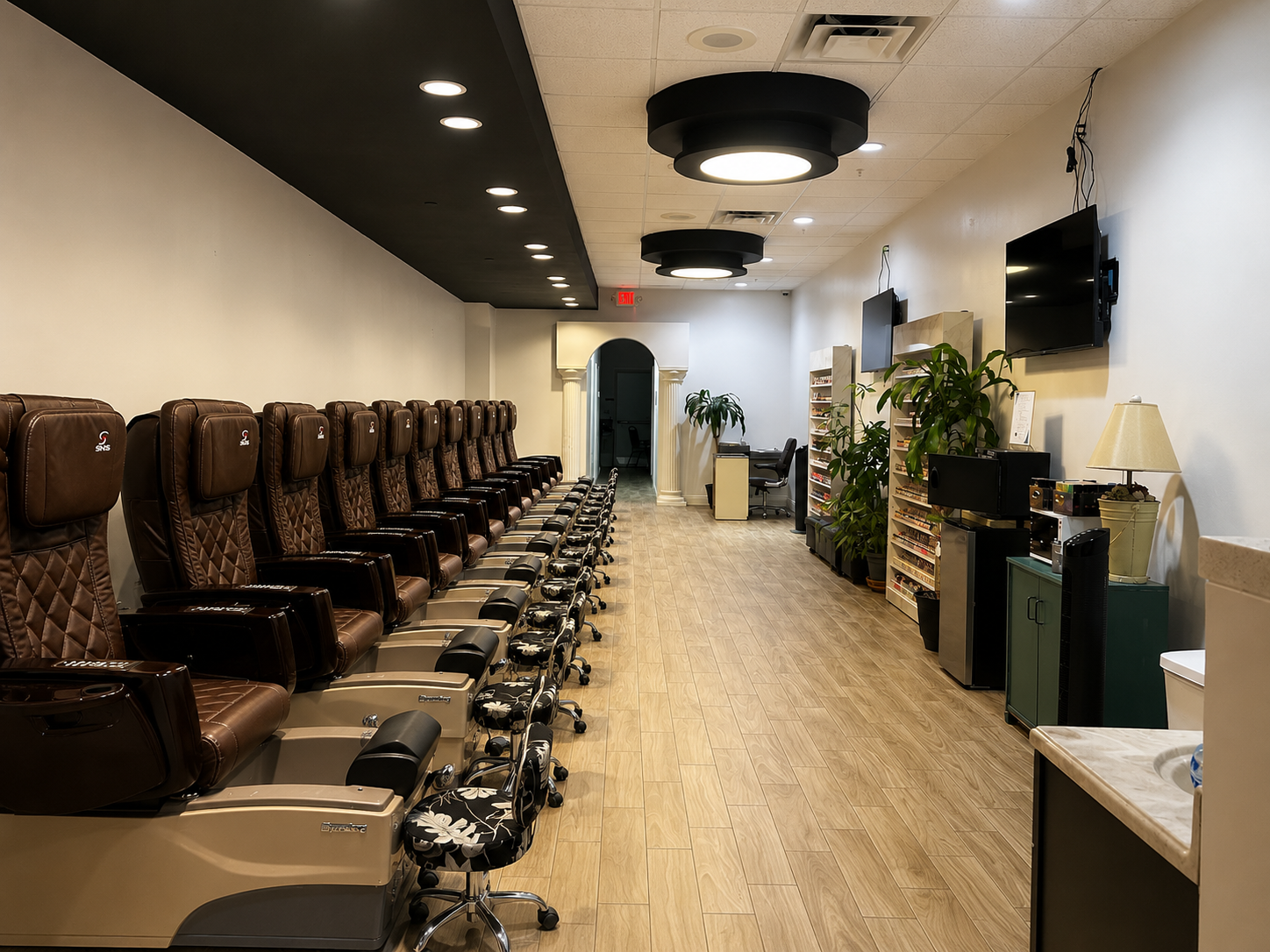 Wide view of the Ocean Nails interior with polish displays, plants, and flat-screen TVs
